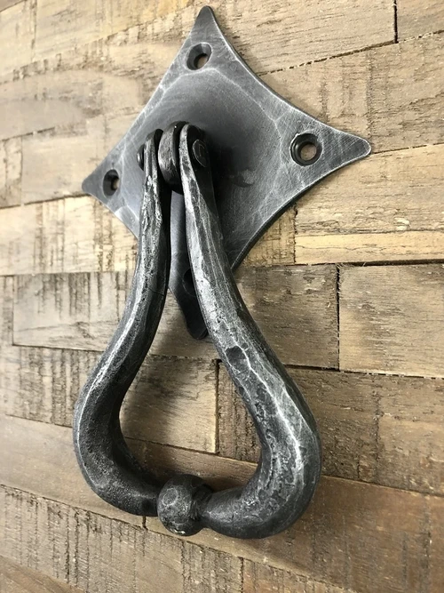 Schönes Design ist dieser Türklopfer aus Schmiedeeisen für die rustikale Holztür.