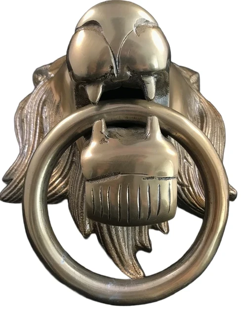 A lion's head, made of aluminum in a brass color, as a door knocker