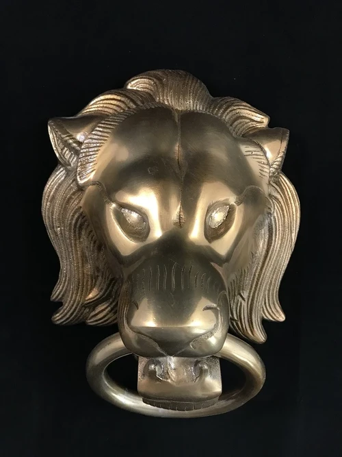 A lion's head, made of aluminum in a brass color, as a door knocker