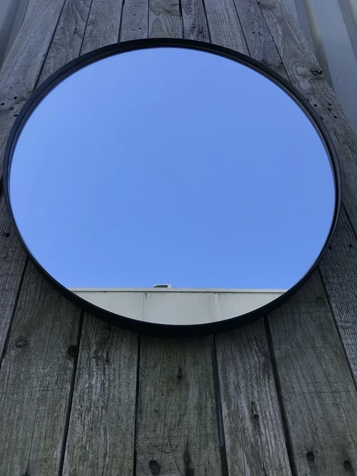 Strakke, moderne spiegel met een zwarte rand, ovaal